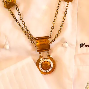 Close-up of the medal on its chain over the chef’s jacket.