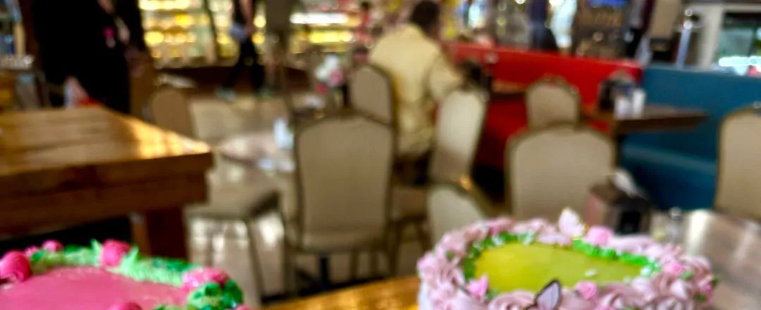 Tables, chairs and booths in a dining room, softly out of focus.