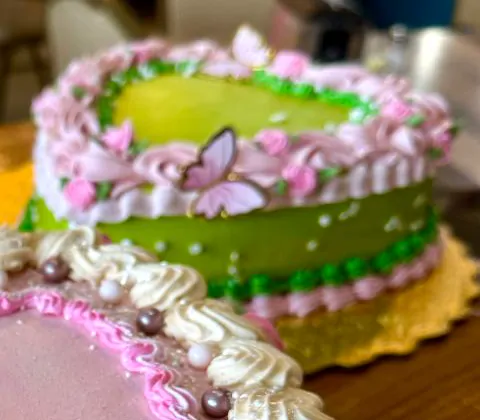 A green heart cake with a pink butterfly and piped pink flowers.