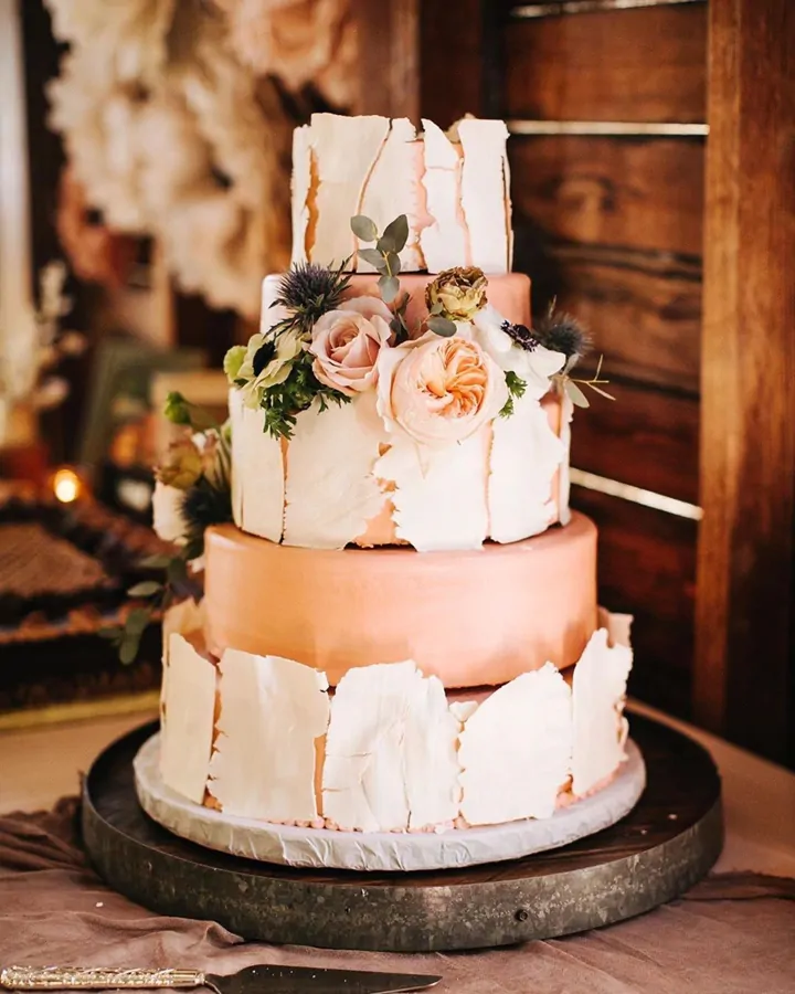A tiered peach and white wedding cake with roses and thistle.